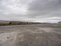 a train traveling down tracks in a rural countryside under a cloudy sky and a few people