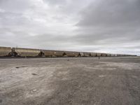 a train traveling down tracks in a rural countryside under a cloudy sky and a few people