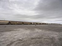 a train traveling down tracks in a rural countryside under a cloudy sky and a few people