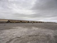 a train traveling down tracks in a rural countryside under a cloudy sky and a few people