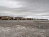 a train traveling down tracks in a rural countryside under a cloudy sky and a few people