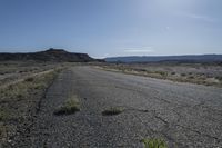 a large dirt field near a small paved highway with the sun behind it with mountains on either side