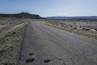 a large dirt field near a small paved highway with the sun behind it with mountains on either side