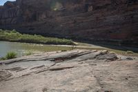 there is a woman sitting on top of a rock at the side of a river