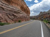 the view from a narrow road in between two large rock formations, and a road with yellow lines