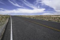 the road on a sunny day stretches out towards the horizon and into a vast desert landscape