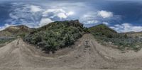 a photo taken from the top of the road looking up at a mountain side, in the background is clouds and a dirt track