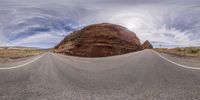 an image of the view looking up at a curving road and mountains in the background