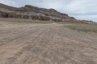 an empty field next to a big mountain with rocks in the background of the picture