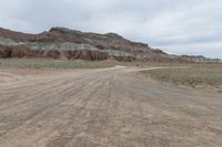 an empty field next to a big mountain with rocks in the background of the picture