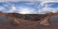 a fish eye view of rock formations in the desert at dusk with cloudy skies above