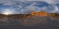 a fish eye view of rock formations in the desert at dusk with cloudy skies above