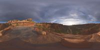 a fish eye view of rock formations in the desert at dusk with cloudy skies above