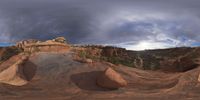 a fish eye view of rock formations in the desert at dusk with cloudy skies above