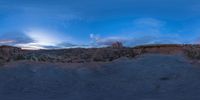 a fish eye view of rock formations in the desert at dusk with cloudy skies above