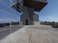 the exterior of a building next to a large glass wall looking out on the water