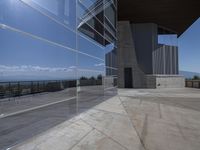 the exterior of a building next to a large glass wall looking out on the water