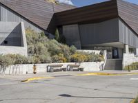 a building with benches and an arrow sign in front of it on the side of the road