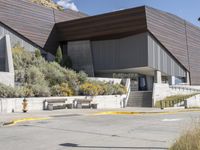 a building with benches and an arrow sign in front of it on the side of the road