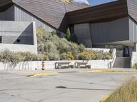 the entrance to a modern building surrounded by tall grass and shrubs, with blue skies