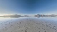 a view from the water of a sandy beach in arizona's death valley to mountains