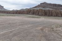 an empty field next to a big mountain with rocks in the background of the picture