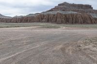 an empty field next to a big mountain with rocks in the background of the picture