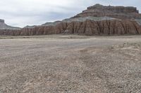 an empty field next to a big mountain with rocks in the background of the picture