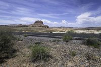 the gravel is brown and there are mountains in the distance from the asphalt road with rocks