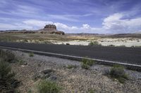 the gravel is brown and there are mountains in the distance from the asphalt road with rocks