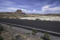 the gravel is brown and there are mountains in the distance from the asphalt road with rocks