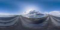 a fish eye photo of a mountain lake with clouds and sky behind it taken in fish - eye mode