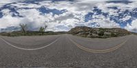 the road has some yellow lines and white clouds in the sky while people are riding bikes on it