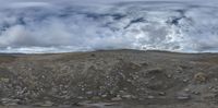 an aerial view of mountains covered with rocks and gravel, on a cloudy day, under a dark sky