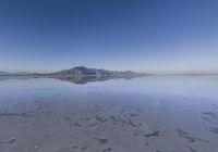 a lone mountain sitting in the middle of an expanse of water with lots of sand and hills