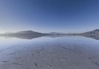 a lone mountain sitting in the middle of an expanse of water with lots of sand and hills