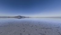 a lone mountain sitting in the middle of an expanse of water with lots of sand and hills