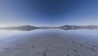 a lone mountain sitting in the middle of an expanse of water with lots of sand and hills