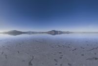 a lone mountain sitting in the middle of an expanse of water with lots of sand and hills