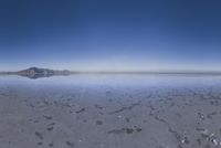 a lone mountain sitting in the middle of an expanse of water with lots of sand and hills