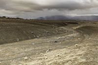 a cloudy day shows rocks and sheep grazing on the plain under an overcast sky