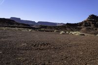 a man standing on top of a sandy field next to some mountains with snow capped mountains