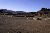 a man standing on top of a sandy field next to some mountains with snow capped mountains