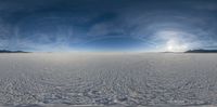 the sun is seen through the clouds above a wide field of snow in a mountain