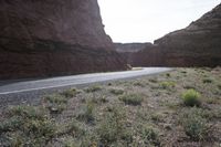 a person riding a motorcycle along a narrow road through rocks and sand cliffs a grassy area on both sides