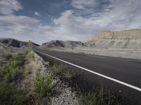 there is a road with no traffic along it next to a cliff and an open field with grass