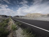 there is a road with no traffic along it next to a cliff and an open field with grass