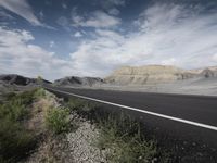 there is a road with no traffic along it next to a cliff and an open field with grass