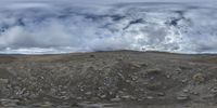 an aerial view of mountains covered with rocks and gravel, on a cloudy day, under a dark sky