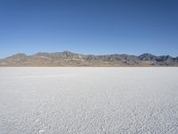 mountains surround a wide plain covered with snow in the background, and a clear sky